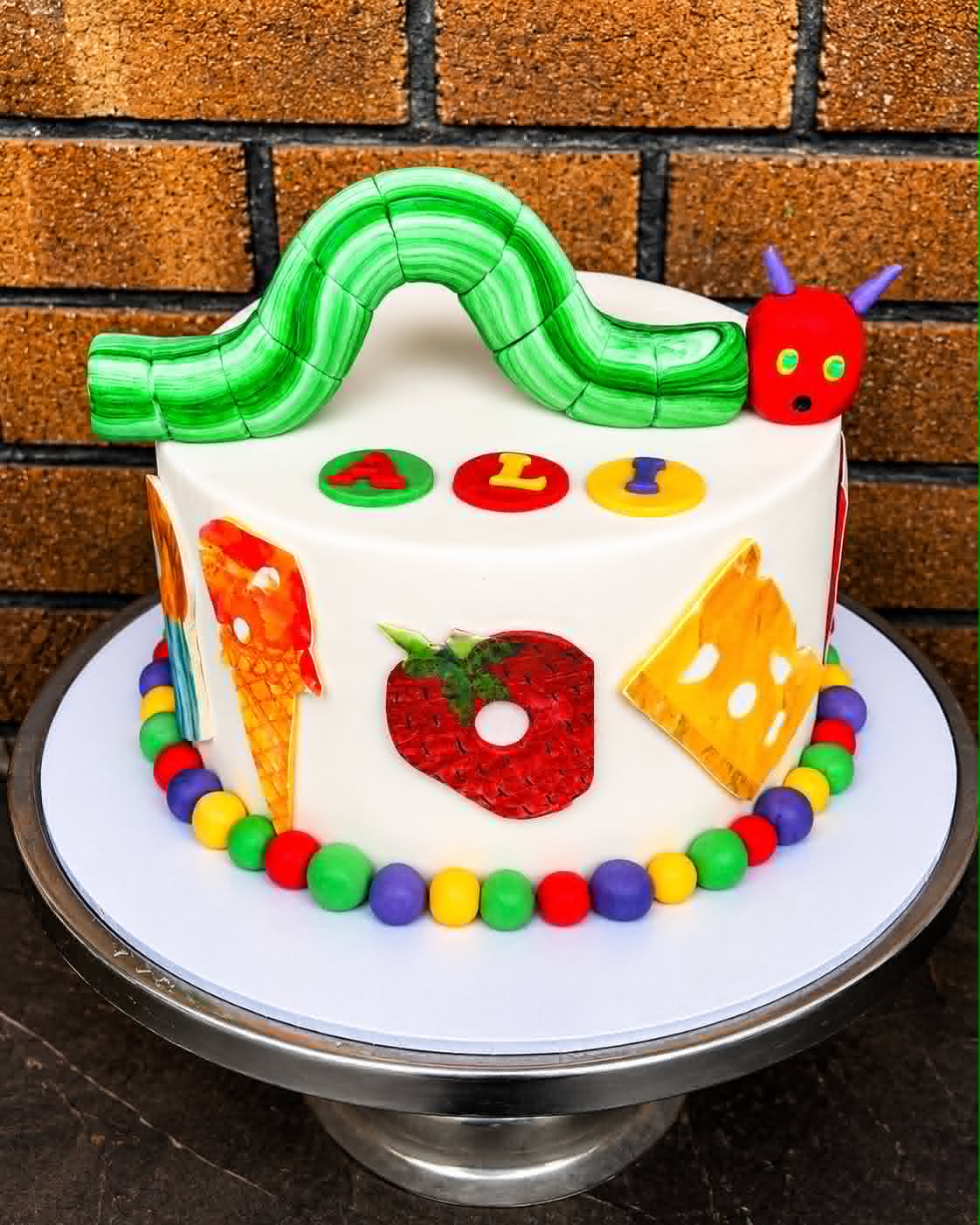 Very Hungry Caterpillar birthday cake for Ali with fondant caterpillar arch and food edible decorations
